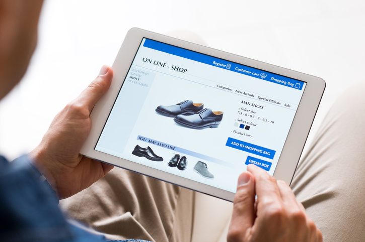 En man som tittar på webbsida för online-shopping av skor